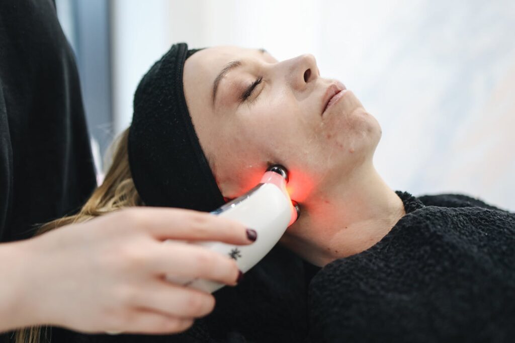 An adult woman receives a laser facial treatment in a modern skincare clinic.
